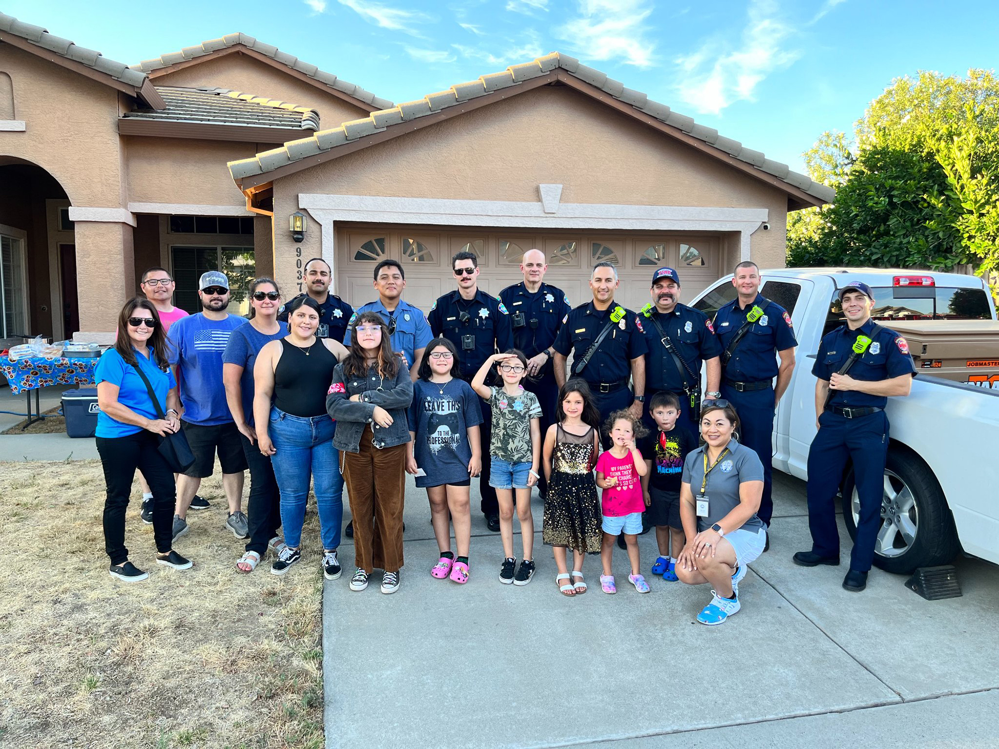 a group of kids and residents with police officers in front of a hosue