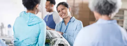 a person at a shelter smiling handing blankets to another person