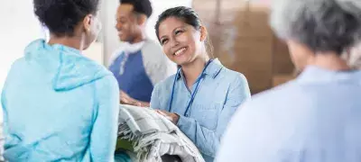 a person at a shelter smiling handing blankets to another person